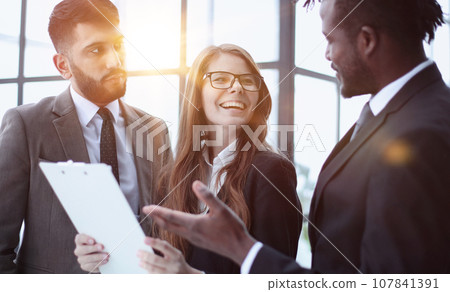 office workers are standing in a corridor of an agency building, holding folders with documents in hand office workers are standing in a corridor of an agency building, holding folders with documents in hand 107841391