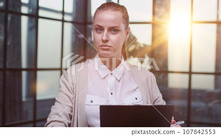 Portrait of a beautiful confident young woman holding a black folder in her hands 107842553