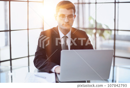 handsome business man in an elegant black suit at a laptop 107842793