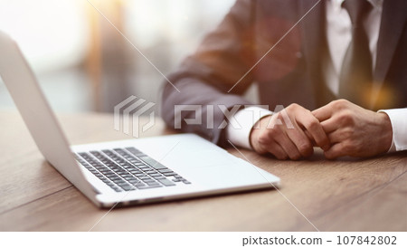 Close-up of a comfortable workplace in the office with a wooden table lying on it and a laptop Close-up of a comfortable workplace in the office with a wooden table lying on it and a laptop 107842802