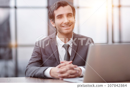 Smiling business man working on laptop at office. 107842864