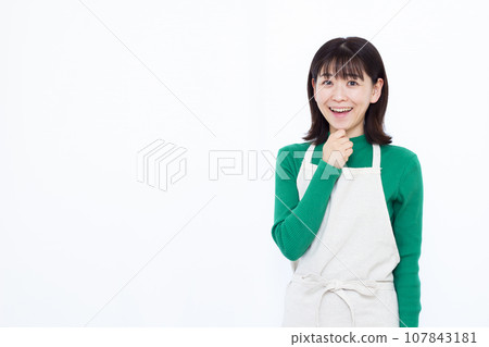 一位 30 多歲的家庭主婦在白色背景前微笑著，看起來很驚訝 107843181