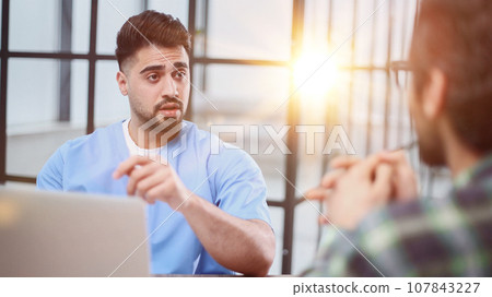 Doctor talking to a patient in a consultation at the office Doctor talking to a patient in a consultation at the office 107843227