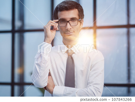 Serious businessman corrects glasses portrait in office 107843266