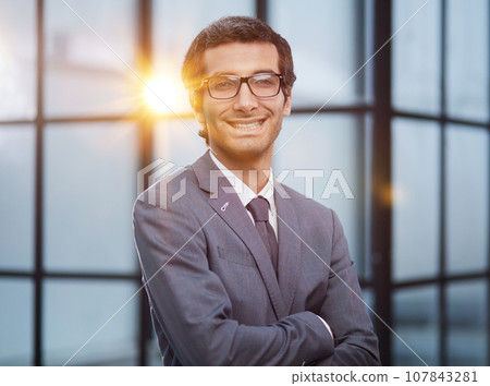 Dedicated to his business. Shot businessman standing with his arms crossed crossed in an office at work. Dedicated to his business. Shot businessman standing with his arms crossed crossed in an office at work. 107843281