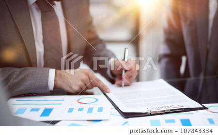 Businessman working at office desk, he is building a growing financial graph using wooden toy blocks. Businessman working at office desk, he is building a growing financial graph using wooden toy blocks. 107843334