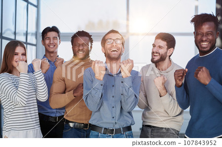 Group of happy managers rejoice at a successful deal by clenching their hands into fists and raising them up 107843952