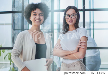 Businesswoman with coworker standing in modern office 107844397