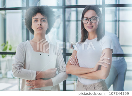 Businesswoman with coworker standing in modern office 107844399