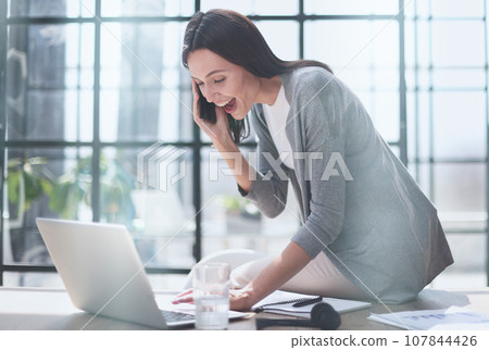Businesswoman with phone in modern office talking 107844426