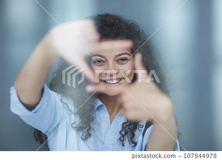 Smiling attractive young business woman in blue shirt posing on gray background 107844978