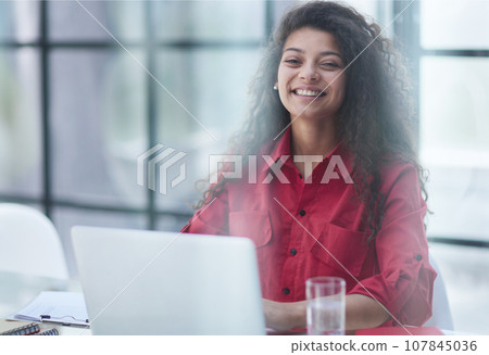 Photo of joyful nice woman using laptop and smiling while sitting 107845036