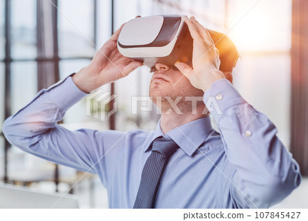 businessman in virtual reality headset in the office businessman in virtual reality headset in the office 107845427