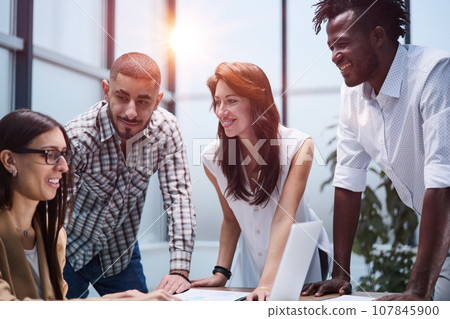 Happy young female worker discussing online project, showing presentation to experienced team leader in glasses. 107845900