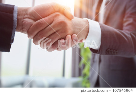 Building a strong business network. two businessmen shaking hands in a modern office. Building a strong business network. two businessmen shaking hands in a modern office. 107845964