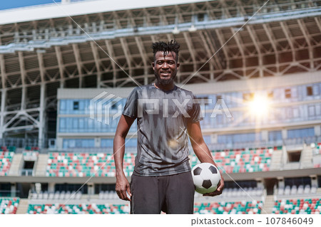 confident black football player holding the ball in his hand at the stadium confident black football player holding the ball in his hand at the stadium 107846049