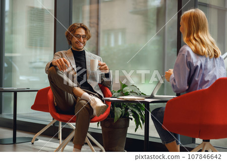 Two diverse business colleagues working together on project sitting in modern coworking 107846642