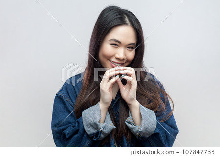 Portrait of mysterious brunette woman in blue denim jacket has interesting plan in mind, intention doing something, everything goes according scheme. Indoor studio shot isolated on gray background. Portrait of mysterious brunette woman in blue denim jacket has interesting plan in mind, intention doing something, everything goes according scheme. Indoor studio shot isolated on gray background. 107847733