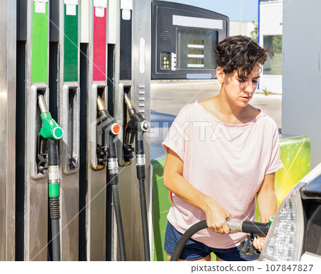 Smiling woman refueling her car in gas station 107847827