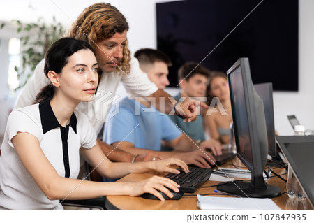 Interested girl attending computer class under guidance of male teacher Interested girl attending computer class under guidance of male teacher 107847935
