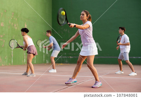 Expressive resolved fit girl playing frontenis ball friendly match on court 107848001