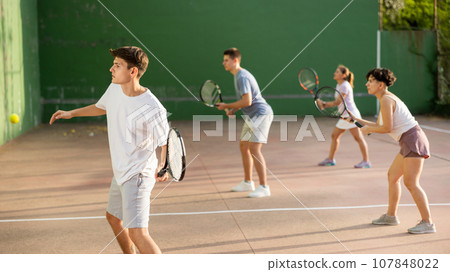 Hispanic guy playing frontenis on open court on summer day Hispanic guy playing frontenis on open court on summer day 107848022