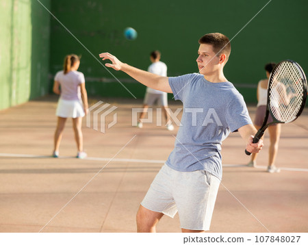 Young male pelota player hitting ball with racket 107848027
