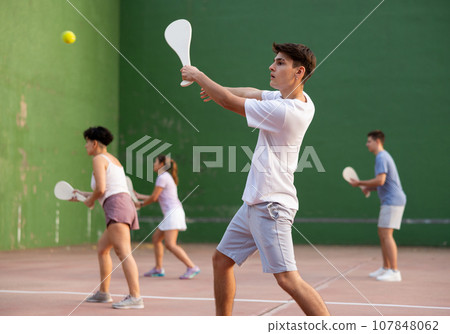 Young man with wooden paleta playing pelota goma on outdoor court 107848062