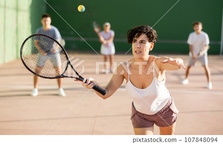 Expressive resolved fit girl playing frontenis ball friendly match on court Expressive resolved fit girl playing frontenis ball friendly match on court 107848094