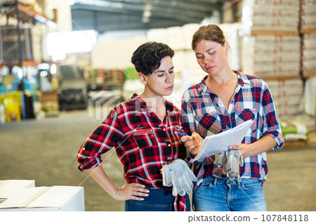 Female warehouse owner and manager keep track of products in warehouse 107848118