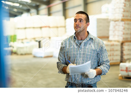 Man checking documentation in warehouse Man checking documentation in warehouse 107848246