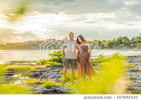 A happy, mature couple over 40, enjoying a leisurely walk on the waterfront On the Sunset, their joy evident as they embrace the journey of pregnancy later in life A happy, mature couple over 40, enjoying a leisurely walk on the waterfront On the Sunset, their joy evident as they embrace the journey of pregnancy later in life 107848320