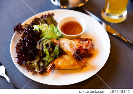 Fried spring rolls with vegetables and shrimps with sauce and salad Fried spring rolls with vegetables and shrimps with sauce and salad 107848345