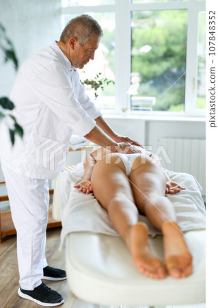 male masseur giving massage to female patient 107848352