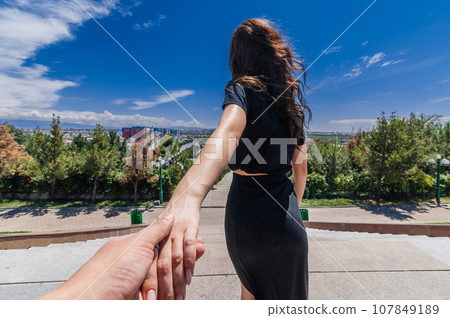 Follow me to Shymkent in Kazakhstan. Young woman holds hand against the background of city Follow me to Shymkent in Kazakhstan. Young woman holds hand against the background of city 107849189