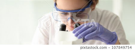 Concentrated scientist in protective goggles examines sample 107849754
