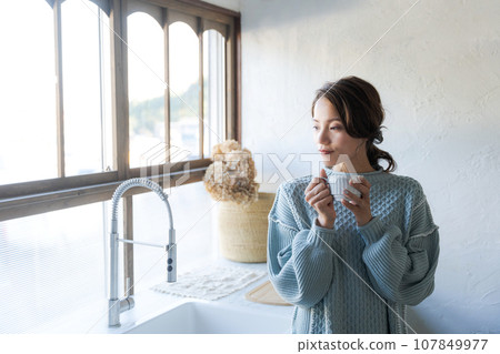 woman in sweater drinking coffee woman in sweater drinking coffee 107849977