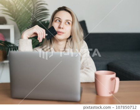 Young woman holding credit card and using laptop computer. 107850712