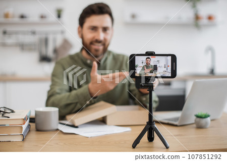 Male blogger unboxing new receiving digital device on camera Male blogger unboxing new receiving digital device on camera 107851292