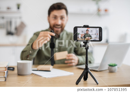 Happy man showing off wristwatch during video blogging 107851395