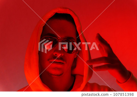 Red background light studio close-up portrait of a male model with a mustache and beard wearing sunglasses 107851398