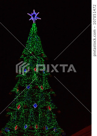 Decorated Christmas tree with multi-colored lights at night 107851472
