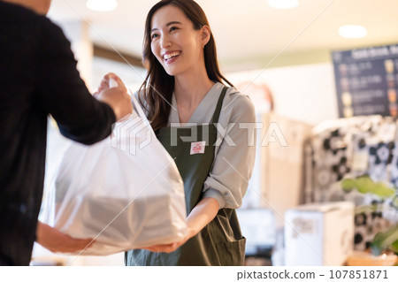 A young female clerk handing over products A young female clerk handing over products 107851871