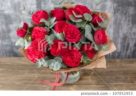 Red Beautiful bouquet of mixed flowers in woman hand. Floral shop concept . Beautiful fresh cut bouquet. Flowers delivery 107852953