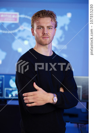 Male Cybersecurity Analyst in large Cyber Security Operation Center SOC handling Threats 107853280