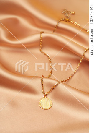 Golden necklace with pendant on silk background Golden necklace with pendant on silk background 107854143