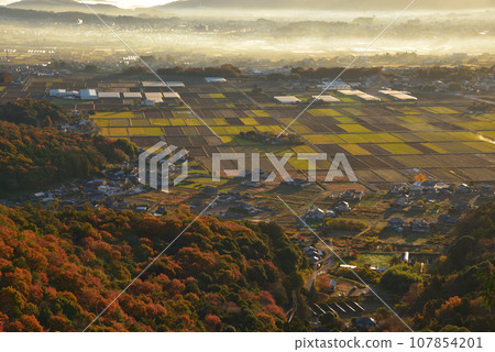 View of the foothills of Mt. Okoyama and the countryside colored by the morning sun from the small peak on the south side of Mt. Okoyama in late autumn 107854201
