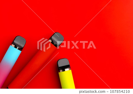 Disposable electronic cigarettes on red background close up 107854210