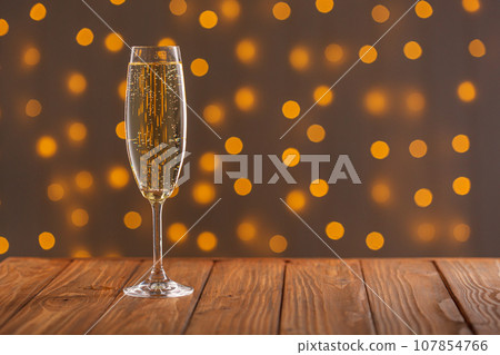 Glasses with champagne on a wooden background against a bokeh background of lights 107854766