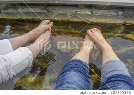 Two people relaxing by soaking their tired feet in the footbath Two people relaxing by soaking their tired feet in the footbath 107855376